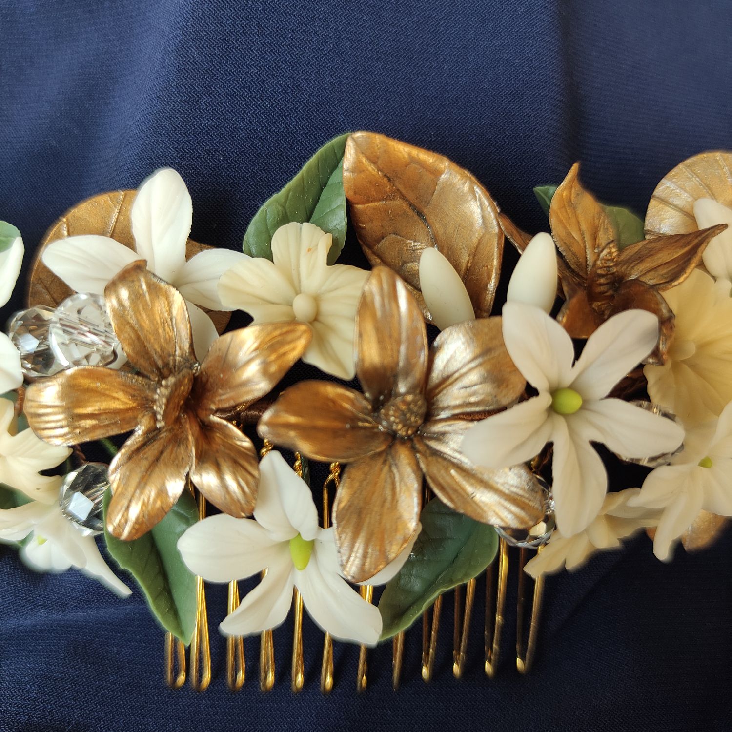 peinecillo orfir Elegant wedding hair accessory with white and gold flowers, green leaves and crystal details.